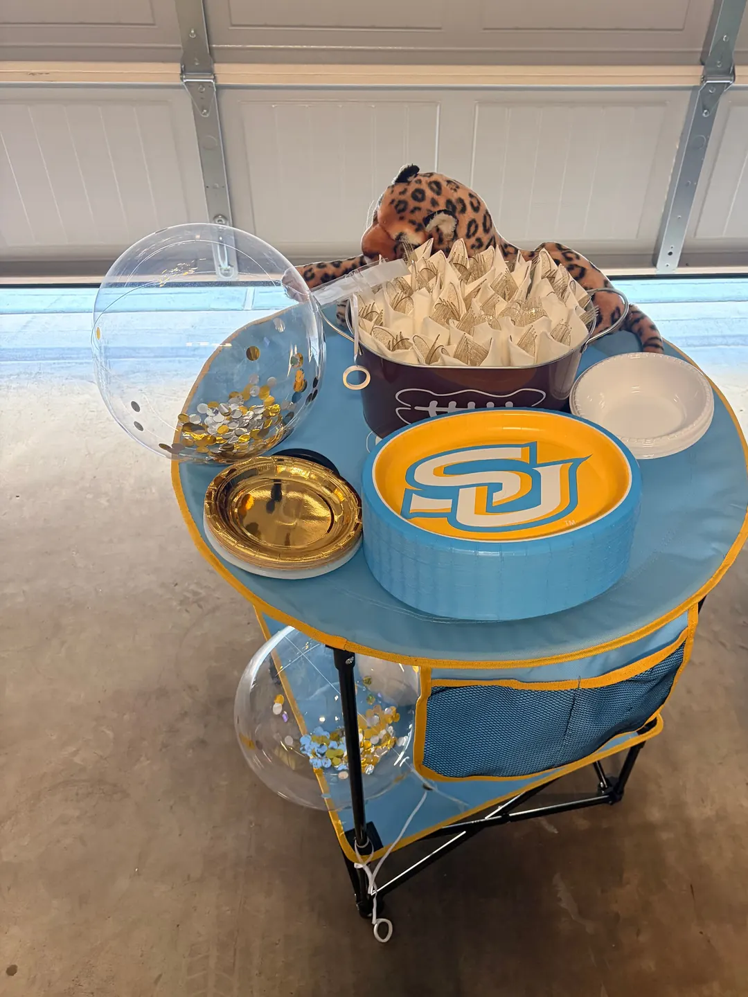 Southern University plates, confetti balloons and a stuffed Jaguar on a blue and gold utensil table