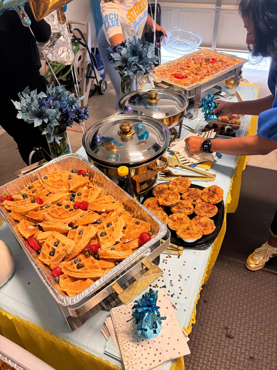 A Bayou Fork Kitchen catering spread with waffles, fresh berries, baked bites and shrimp and grits