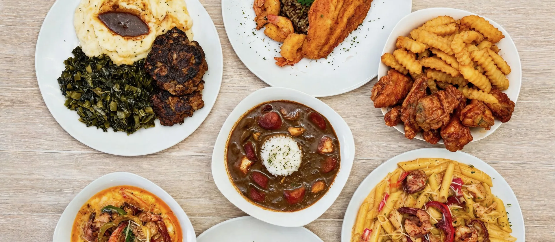 Bayou Fork Kitchen plates from above: gumbo, fried catfish and shrimp, wings and fries, shrimp and grits, Cajun pasta, and greens with mashed potatoes